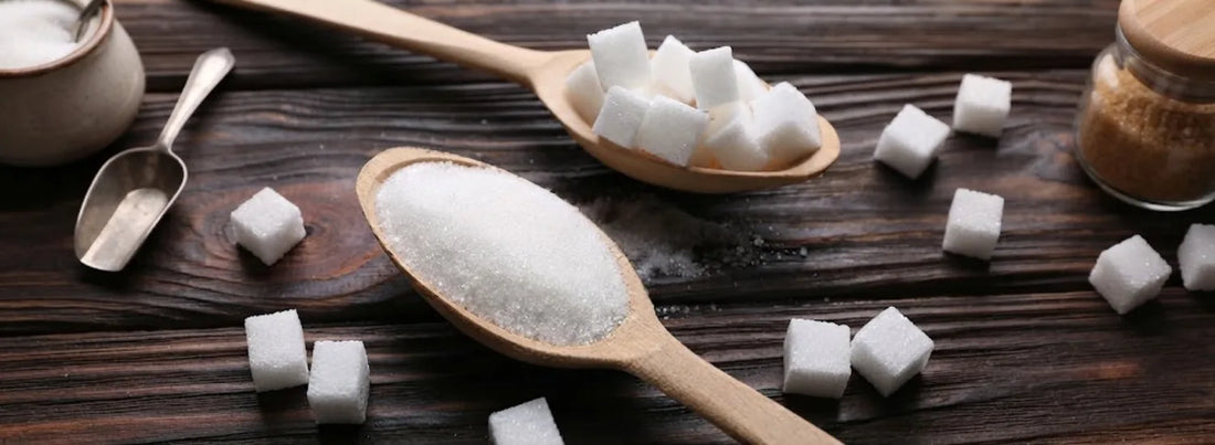 Wooden spoons full of white sugar and sugar cubes.