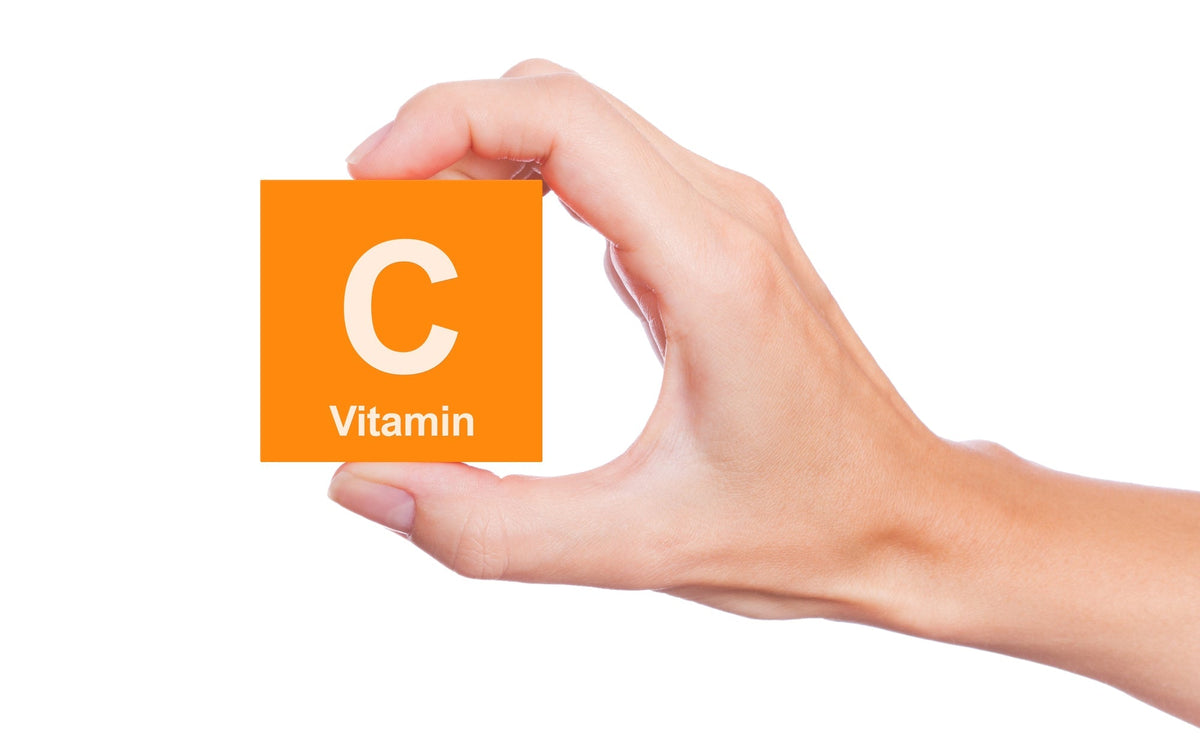 A hand holding up an orange square labeled as Vitamin C.