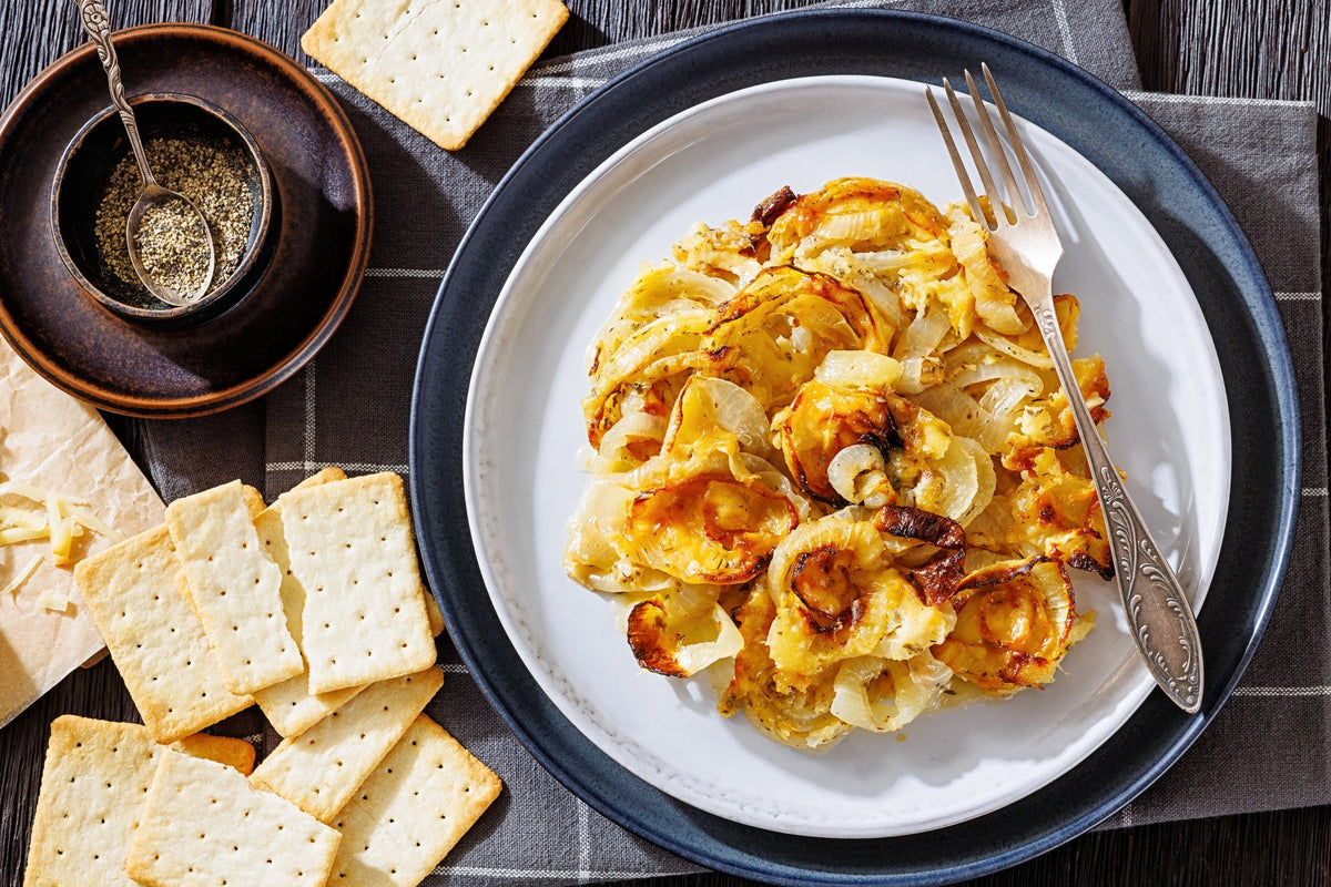 Top-down view of onion casserole on a plate, next to a variety of crackers.