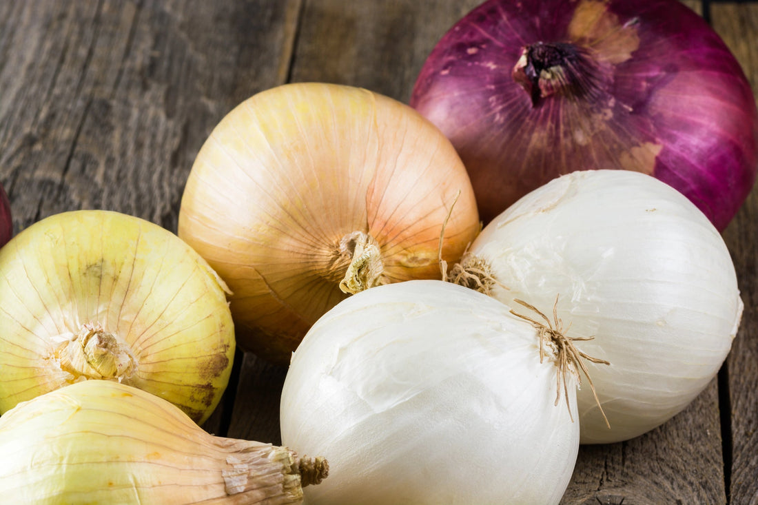 A variety of red, yellow, and white onions on a table.