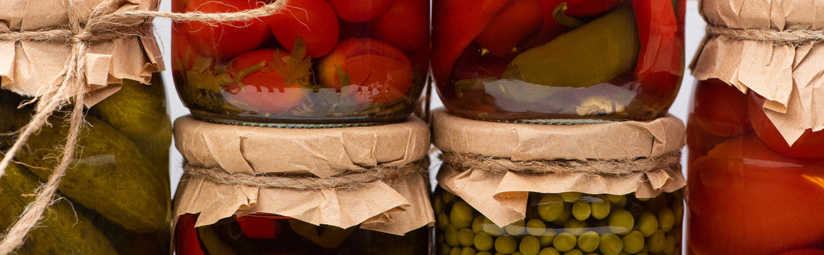 A closeup of various jars of pickled vegetables stacked together.