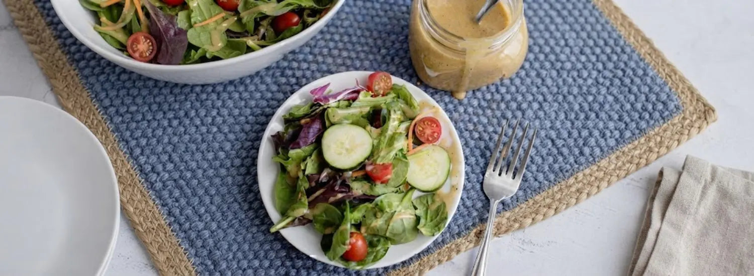 A photo of a fresh cucumber and tomato salad drizzled in Vidalia onion vinaigrette, with a jar of the smooth yellow vinaigrette sitting next to it.