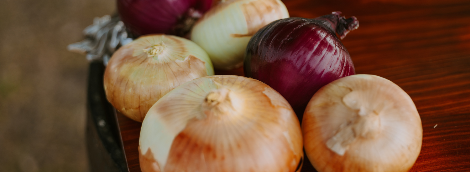 An assortment of orange-yellow Vidalia onions next to several red sweet onions, starkly contrasting one another.
